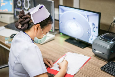 Nurse writing in paper at table in hospital