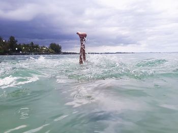 Man swimming in sea against sky