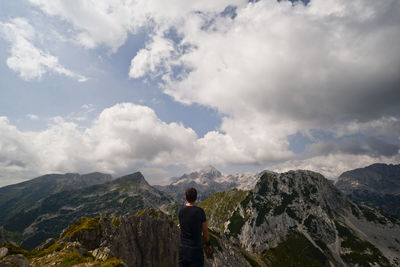 Rear view of man standing on mountain against sky