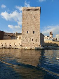 Castle tower by river against sky