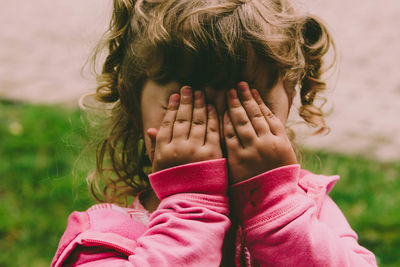 Close-up of girl covering face while standing outdoors