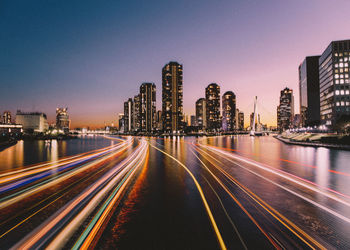 Light trails on road against buildings and sky