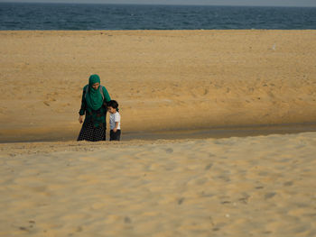 Mother and young boy walking on beach