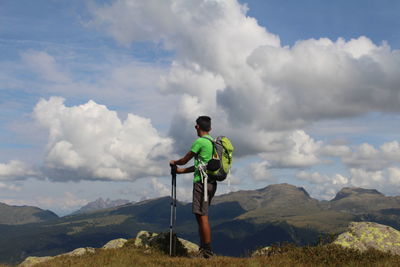 Rear view of man standing on mountain against sky