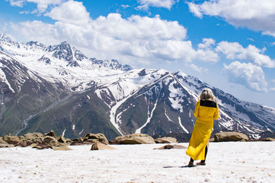 Rear view of woman standing on snowcapped mountain