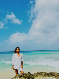 Rear view of woman standing at beach against sky