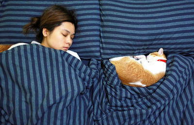 Mid adult woman with cat sleeping on bed