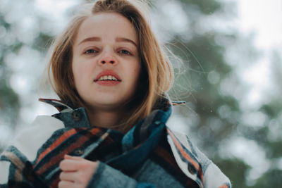 Portrait of young woman standing against trees