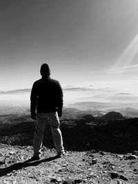 Rear view of man standing on mountain against sky