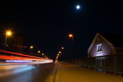 Light trails on road amidst illuminated buildings in city at night