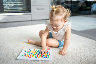 Cute girl playing with multi colored toy at home