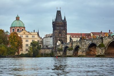 Arch bridge over river against buildings in city