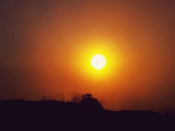 Scenic view of silhouette field against orange sky