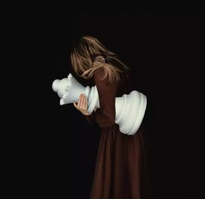 Portrait of young woman holding toy against black background
