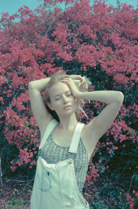 Young woman standing by flowers against tree