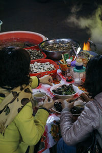 Rear view of people having food at night