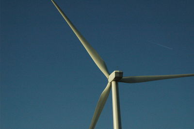 Low angle view of wind turbine against blue sky