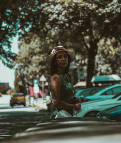 Man wearing hat while sitting in car against trees in city