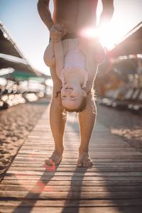 Low section of woman with arms raised against sky