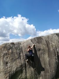 Rear view of woman climbing mountain against blue sky