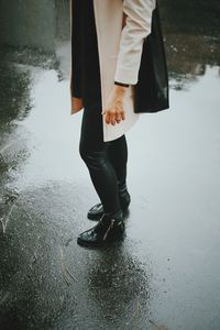 Low section of woman standing by puddle