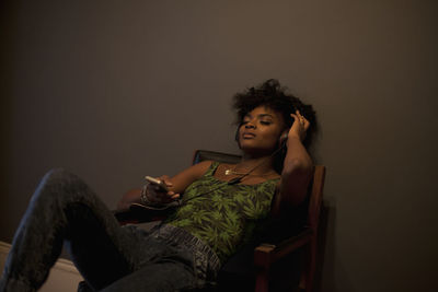 Young woman looking away while sitting on wall at home