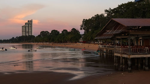 Scenic view of river by buildings against sky during sunset