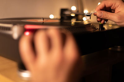 Cropped hand of man playing song on turntable