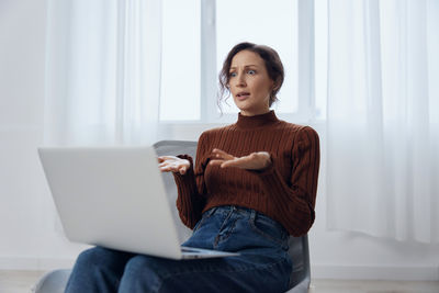 Portrait of young woman sitting on sofa at home