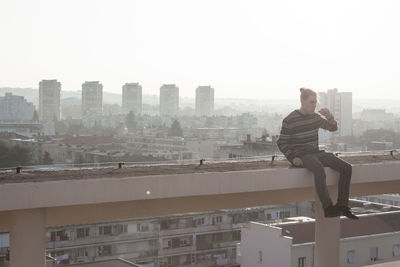 Man and buildings in city against clear sky