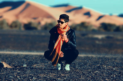 Smiling man crouching on field