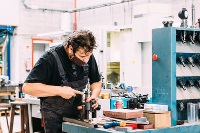 Factory worker wearing uniform working on lathe with drilling machine in contemporary light craftsmanship