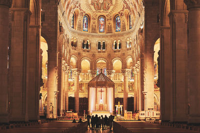 Low angle view of the center alley of a basilica, with silhouettes.
