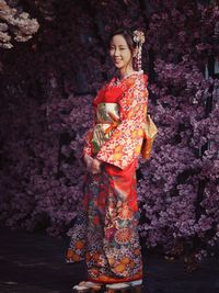 Young woman standing against tree