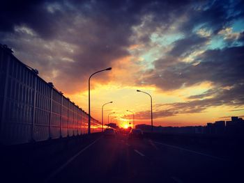 Road by silhouette street against sky during sunset