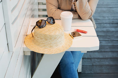 A woman with a glass of coffee sits at a table on the summer veranda of the cafe.