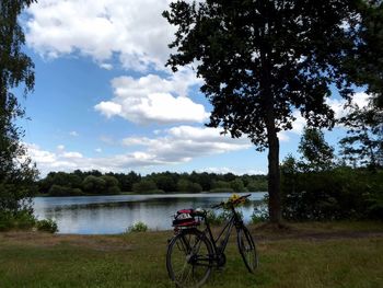 Bicycle by lake against sky