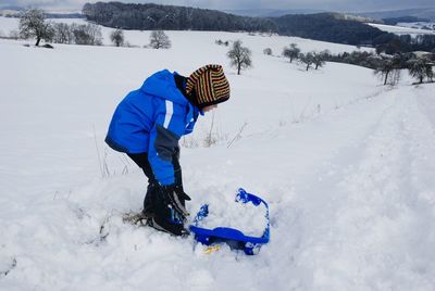 Side view of girl on snowcapped field during winter