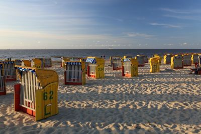 Hooded chairs on beach against sky