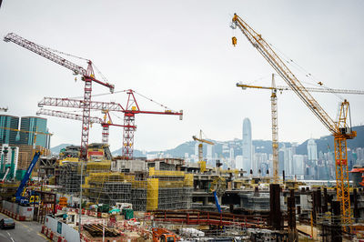 Cranes at construction site against sky in city