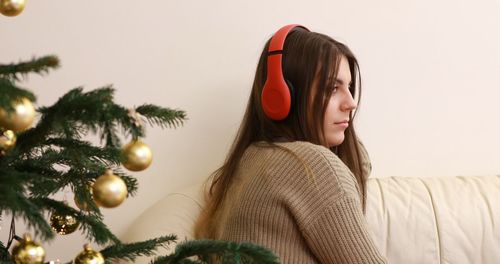 Portrait of woman sitting by christmas tree