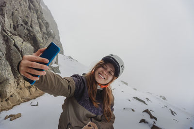 Portrait of young woman standing against mountain