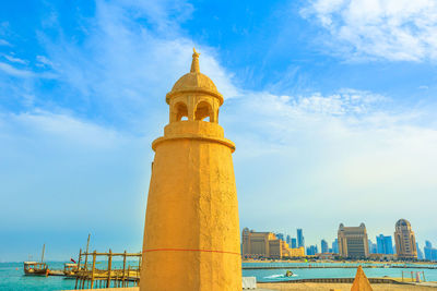 Lighthouse at beach in city against sky