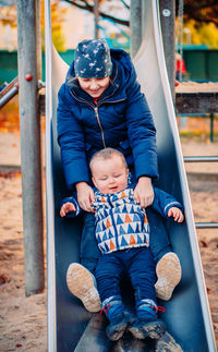 Cute sibling sitting on slide at playground