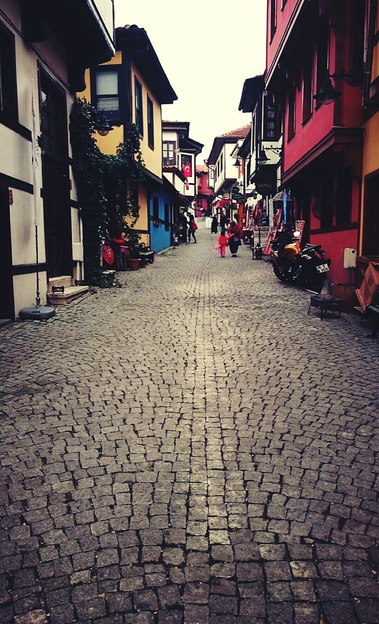 building exterior, architecture, built structure, street, cobblestone, the way forward, city, residential building, residential structure, diminishing perspective, house, in a row, outdoors, incidental people, town, building, paving stone, day, road, vanishing point