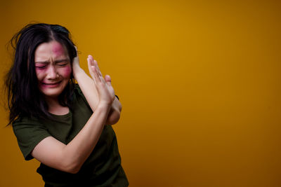 Portrait of beautiful young woman against yellow background