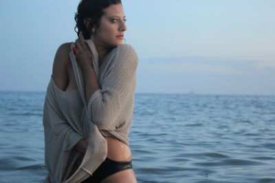 Young woman standing at beach against sky