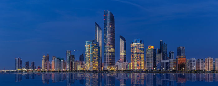 Sea by modern buildings against sky in city