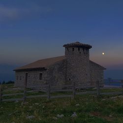 Old building on field against sky during sunset