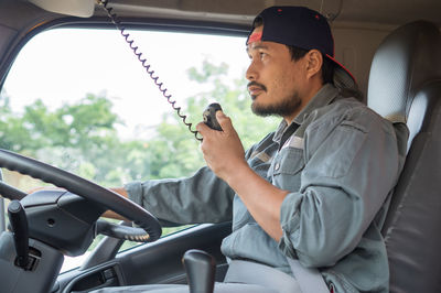 Side view of young man sitting in car